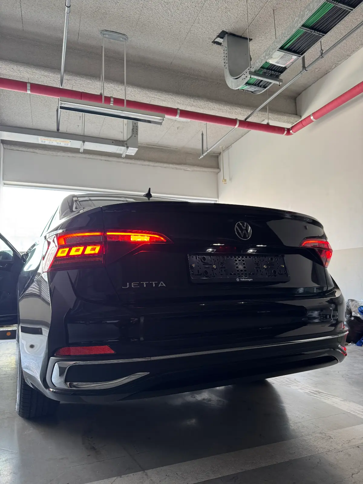 폭스바겐 제타 딥 블랙 펄 프레스티지 2024년식 실물 사진 6/9 - 뒷모습 위주로 촬영된 제타 블랙 색상의 출고사진입니다.